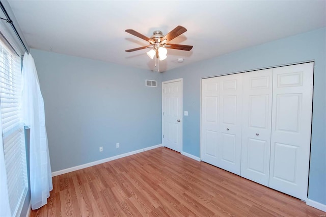 unfurnished bedroom featuring a closet, visible vents, ceiling fan, light wood-type flooring, and baseboards