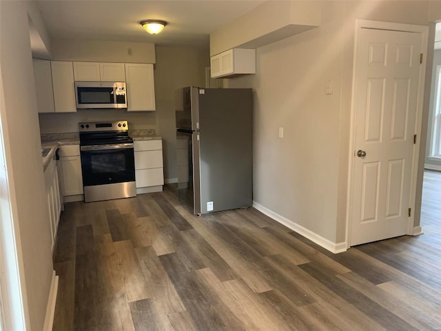 kitchen with dark wood-type flooring, appliances with stainless steel finishes, and white cabinets