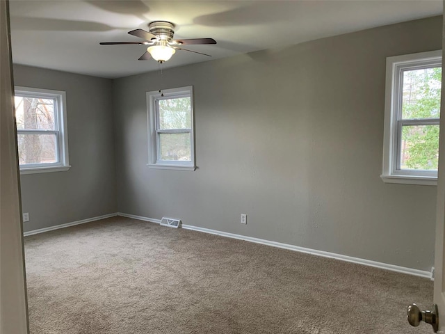 empty room featuring ceiling fan, light carpet, and a wealth of natural light