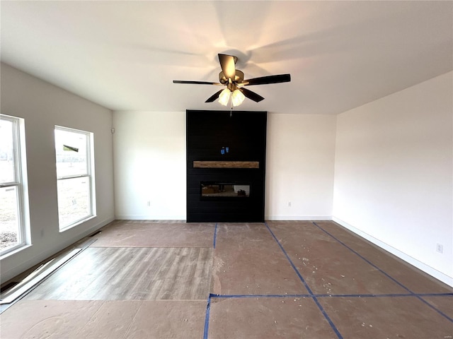 unfurnished living room with a large fireplace and ceiling fan