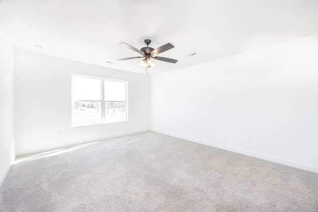 carpeted spare room featuring visible vents, ceiling fan, and baseboards