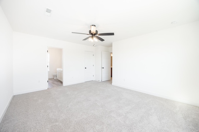 spare room with baseboards, light colored carpet, visible vents, and ceiling fan