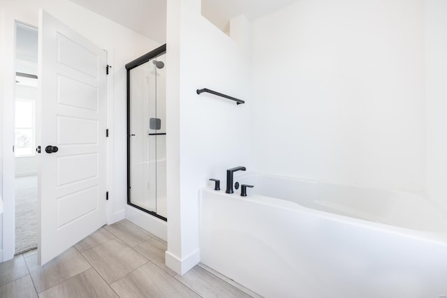 bathroom featuring a garden tub and a shower stall