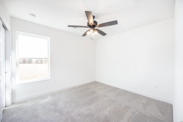 carpeted spare room featuring a ceiling fan and baseboards