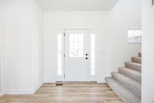 foyer featuring stairway, baseboards, light wood-type flooring, and visible vents