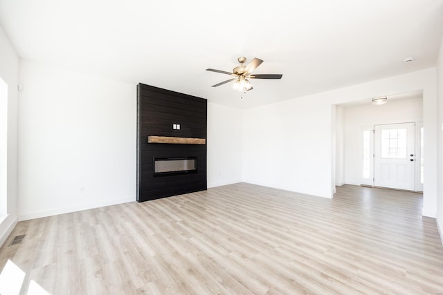 unfurnished living room featuring light wood-type flooring, visible vents, a ceiling fan, a fireplace, and baseboards