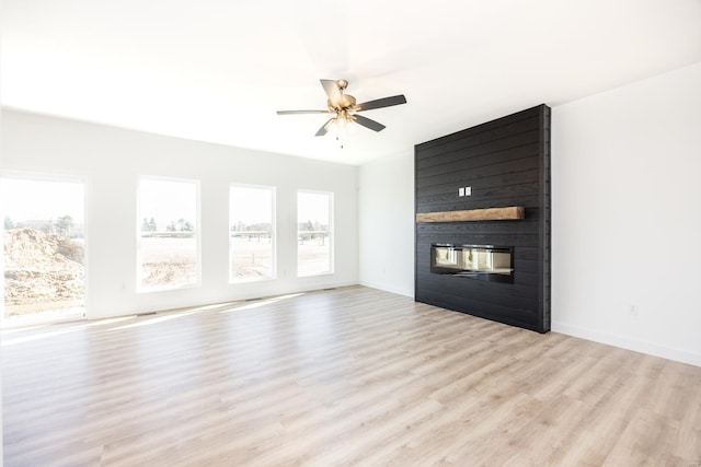 unfurnished living room with ceiling fan, baseboards, light wood-type flooring, and a large fireplace