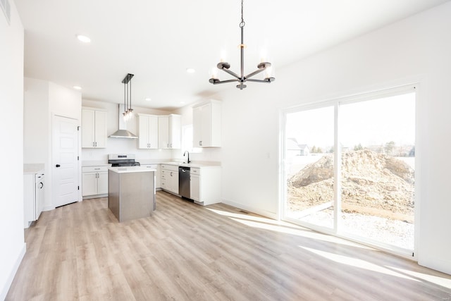 kitchen with a kitchen island, wall chimney range hood, appliances with stainless steel finishes, a notable chandelier, and a sink