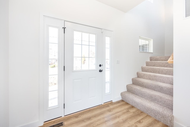 entryway with stairway, light wood-style flooring, and visible vents