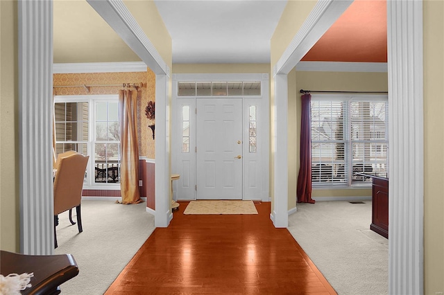 entrance foyer with wood finished floors, carpet flooring, and crown molding