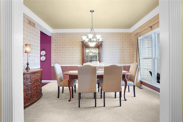 carpeted dining space with crown molding, visible vents, a chandelier, baseboards, and wallpapered walls