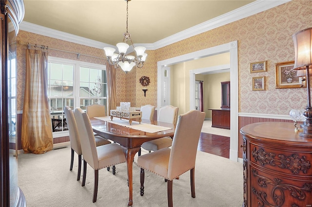 dining space with wallpapered walls, wainscoting, ornamental molding, an inviting chandelier, and carpet floors