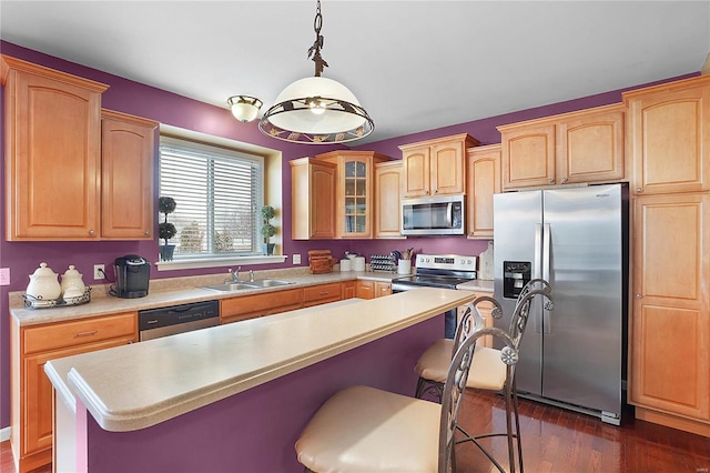 kitchen with a breakfast bar area, stainless steel appliances, a sink, and light countertops