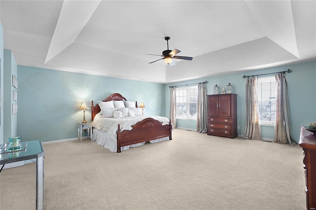 carpeted bedroom with a tray ceiling, ceiling fan, and baseboards