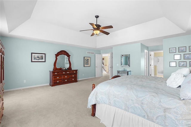 bedroom with light colored carpet, a ceiling fan, baseboards, visible vents, and a raised ceiling