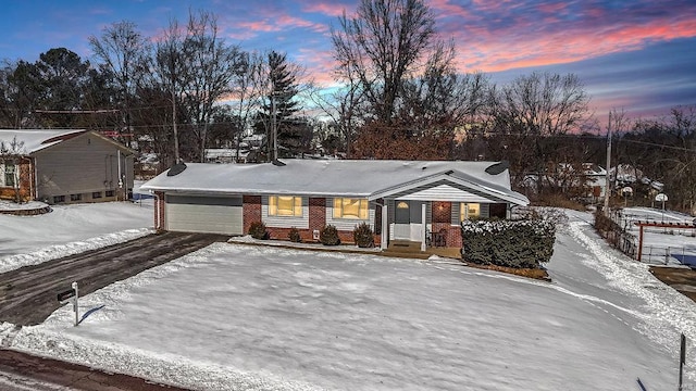 single story home featuring an attached garage, driveway, and brick siding