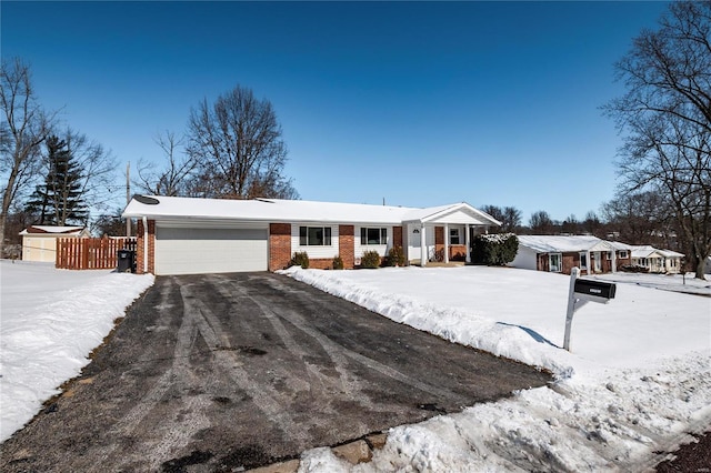 ranch-style house featuring a garage, brick siding, fence, and aphalt driveway