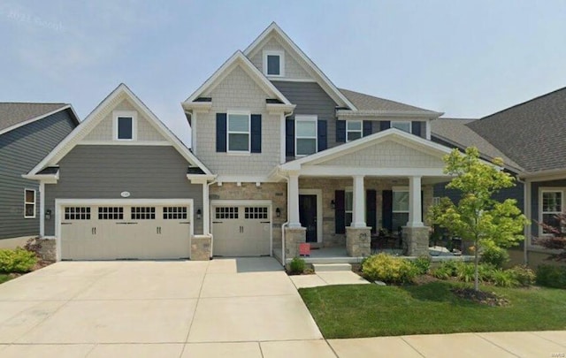 craftsman inspired home featuring stone siding, covered porch, and driveway