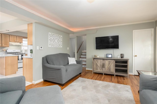 living room featuring light wood-type flooring, baseboards, stairway, and ornamental molding