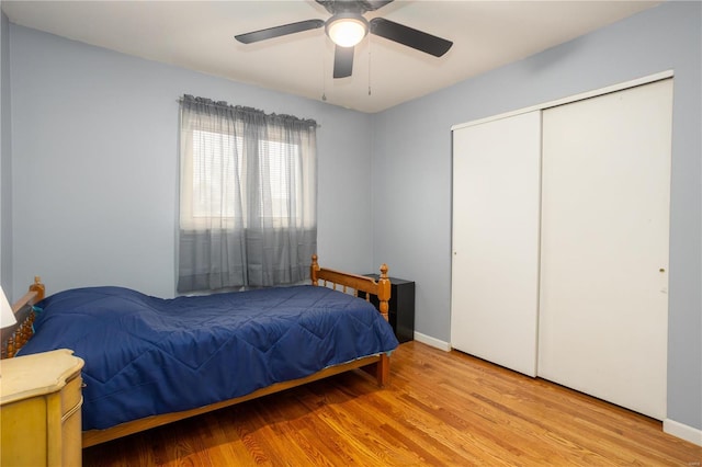 bedroom featuring ceiling fan, a closet, wood finished floors, and baseboards