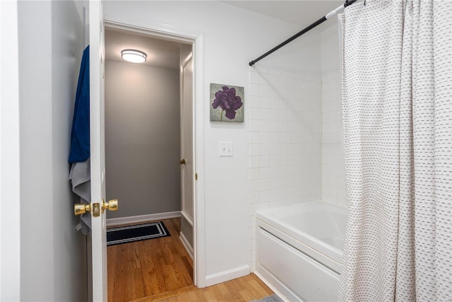 full bath with shower / tub combo, baseboards, and wood finished floors