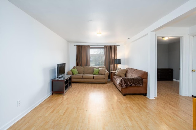 living area featuring baseboards and light wood finished floors