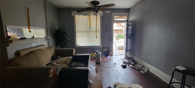 living area featuring ceiling fan, baseboards, and wood finished floors