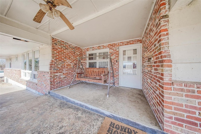 doorway to property featuring a ceiling fan and brick siding