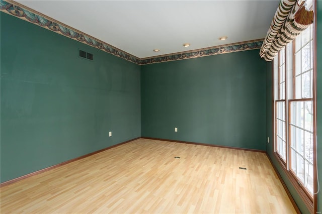 spare room with visible vents, baseboards, and wood finished floors