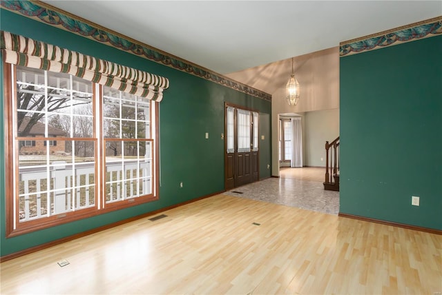 foyer entrance with baseboards, visible vents, stairway, wood finished floors, and vaulted ceiling