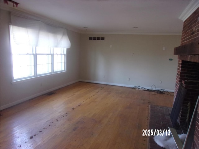 unfurnished living room with visible vents, a brick fireplace, wood finished floors, and ornamental molding