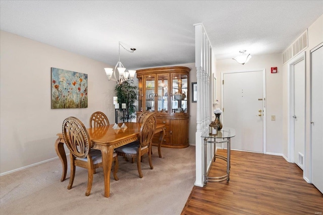 dining area with an inviting chandelier, a textured ceiling, and hardwood / wood-style flooring