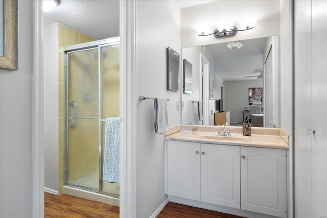 bathroom featuring vanity, hardwood / wood-style flooring, a shower with door, and a textured ceiling