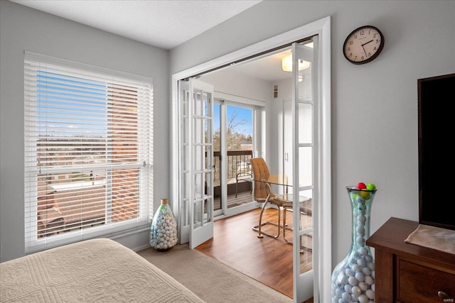 bedroom with light hardwood / wood-style floors, a textured ceiling, and access to outside