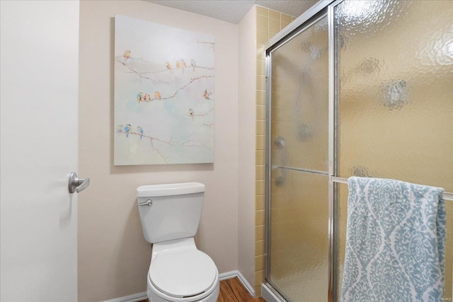 bathroom with wood-type flooring, an enclosed shower, and toilet