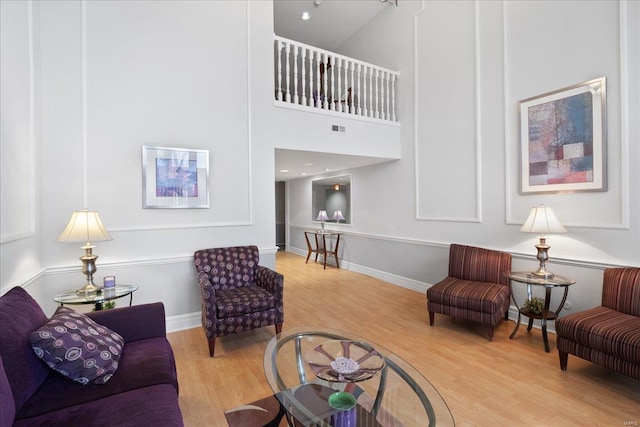 living room with a towering ceiling and light hardwood / wood-style floors