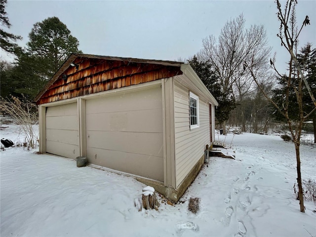 snow covered garage featuring a detached garage