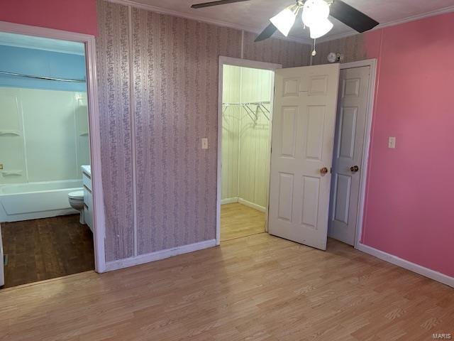 unfurnished bedroom with ceiling fan, ensuite bath, ornamental molding, and light hardwood / wood-style floors