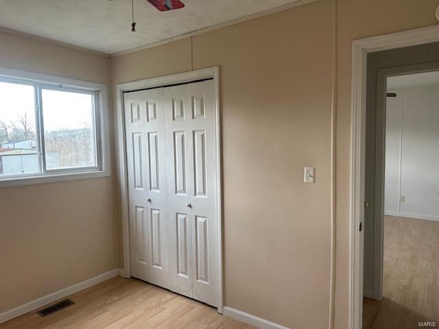 unfurnished bedroom with baseboards, visible vents, a closet, and light wood-type flooring