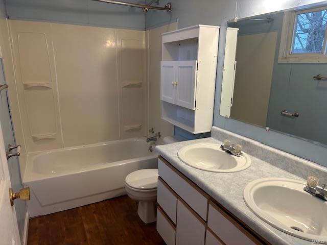full bathroom featuring washtub / shower combination, toilet, wood finished floors, and a sink
