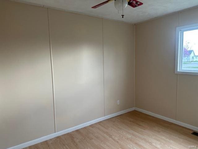 empty room featuring a ceiling fan, baseboards, and light wood-style floors