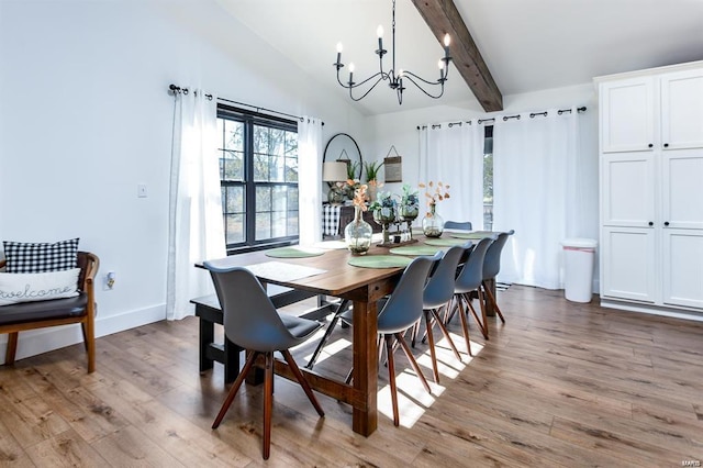 dining area featuring lofted ceiling with beams, a notable chandelier, and light hardwood / wood-style floors