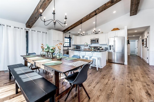 dining area featuring an inviting chandelier, light hardwood / wood-style floors, and lofted ceiling with beams