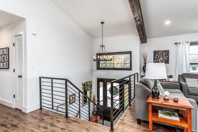 stairs featuring hardwood / wood-style flooring, a chandelier, and beam ceiling