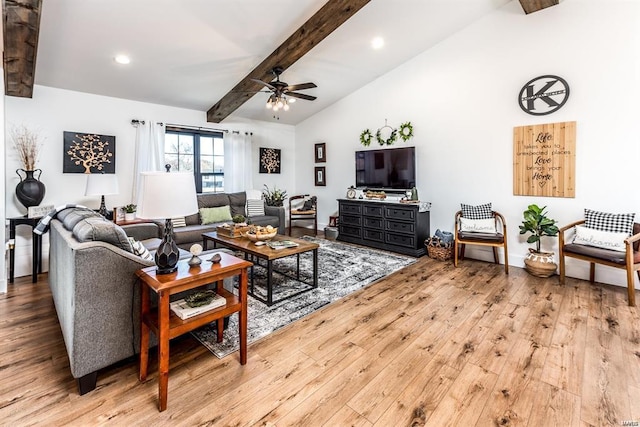 living room featuring ceiling fan, light hardwood / wood-style flooring, and vaulted ceiling with beams