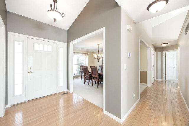 entryway featuring vaulted ceiling, hardwood / wood-style floors, and an inviting chandelier