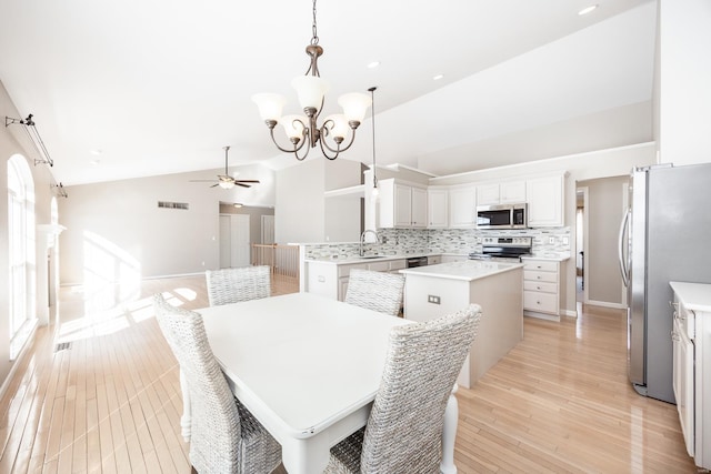 kitchen featuring lofted ceiling, sink, light wood-type flooring, stainless steel appliances, and tasteful backsplash