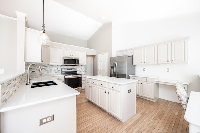 kitchen with appliances with stainless steel finishes, hanging light fixtures, white cabinets, a kitchen island, and sink