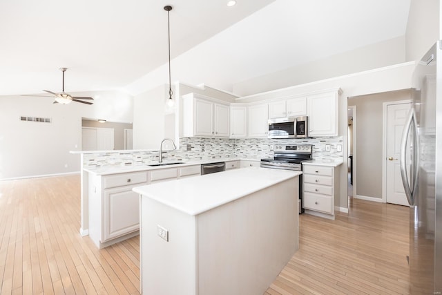 kitchen featuring appliances with stainless steel finishes, decorative light fixtures, white cabinetry, and a kitchen island