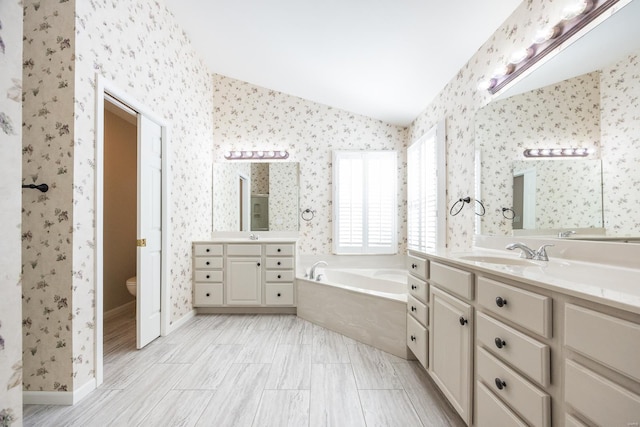 bathroom with vanity, toilet, a bath, and lofted ceiling